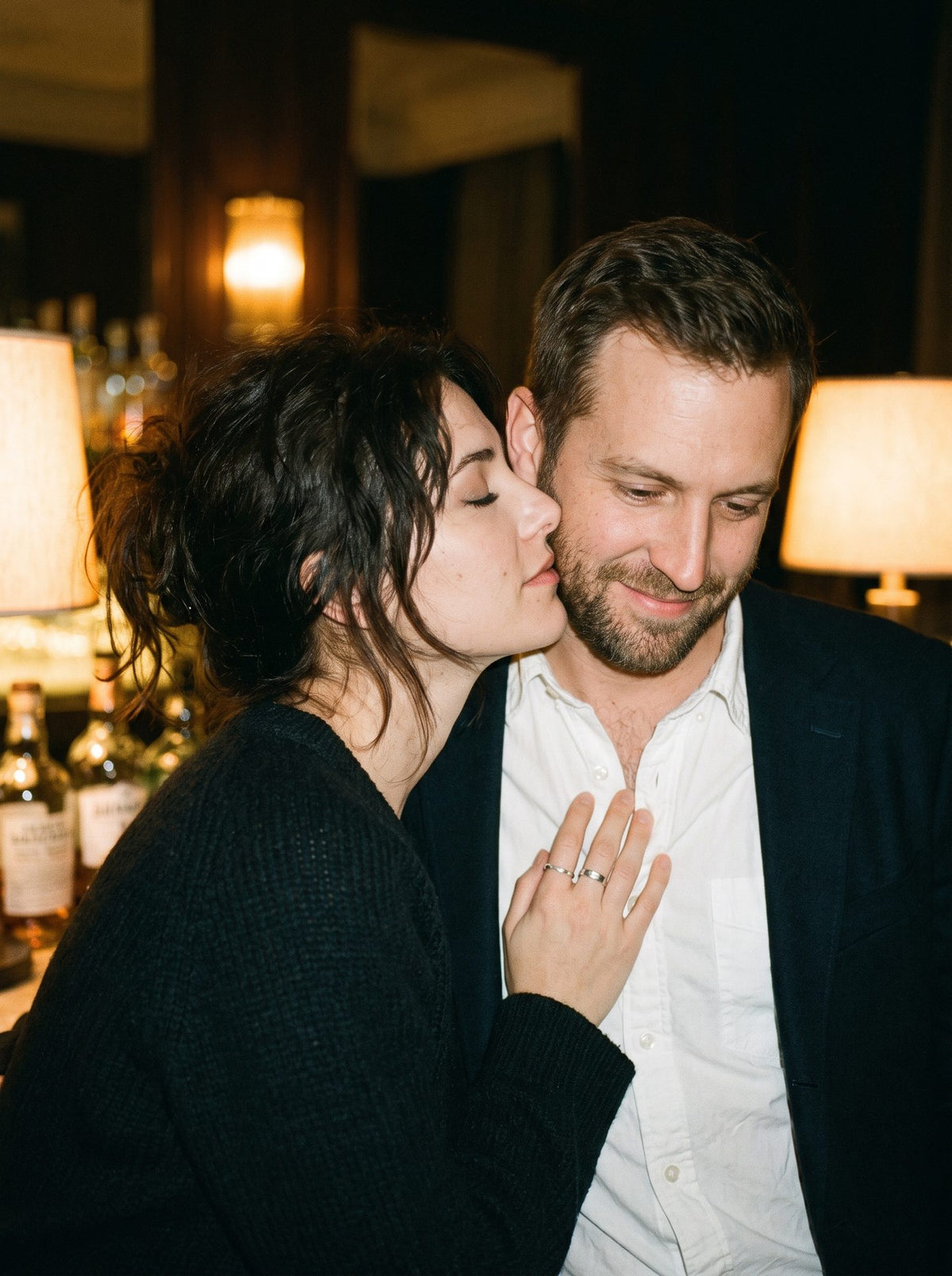 A woman leans into a man's neck, eyes closed
